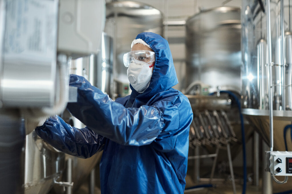 homem trabalhando com roupa protetora e equipamentos de proteção em uma fábrica